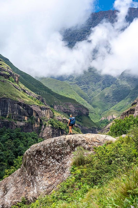 Female hiker standing in front of landscape with mountains and fog, Drakensberg National Park, KwaZulu Natal, South Africa