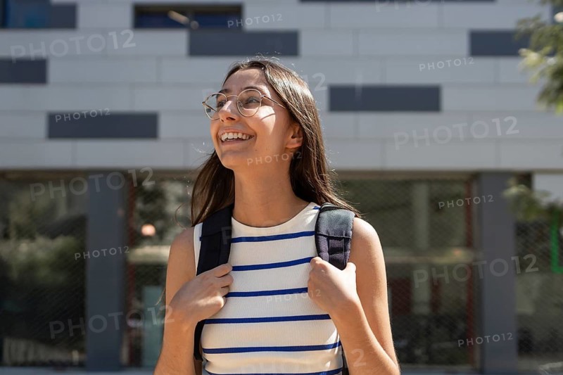 A woman embraces the urban outdoor lifestyle, strolling through the city with confidence. Her backpack and casual attire suggest a blend of style and adventure as she explores the urban environment