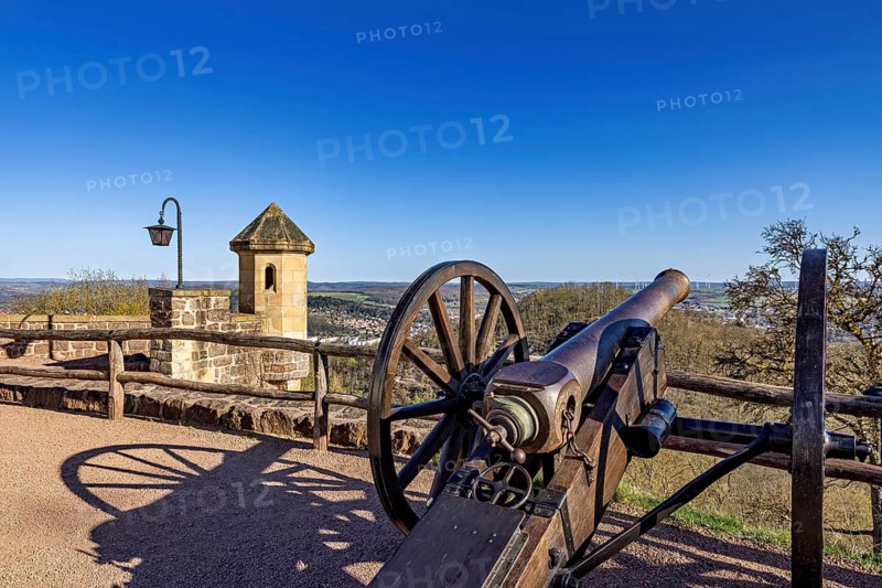 A historic cannon looks out over a clear landscape with a blue sky and a stone lantern in the background, The cannons on the Wartburg entrenchment near Eisenach in Thuringia