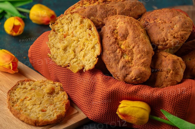 Fresh potato rolls in a basket with orange cloth, one cut open