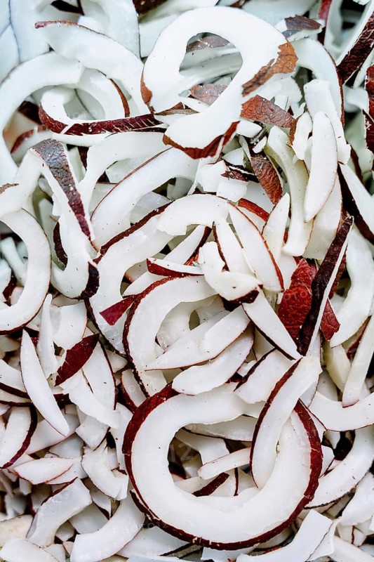 A close up of freshly sliced coconut pieces showcasing the contrast between the white flesh and brown shell. Perfect for food, tropical, or ingredient themed projects