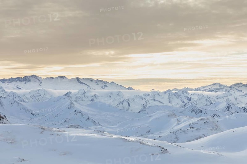 Serene beauty of a snowy mountain range at sunrise, where undisturbed snow blankets the peaks, creating ideal conditions for ski touring enthusiasts