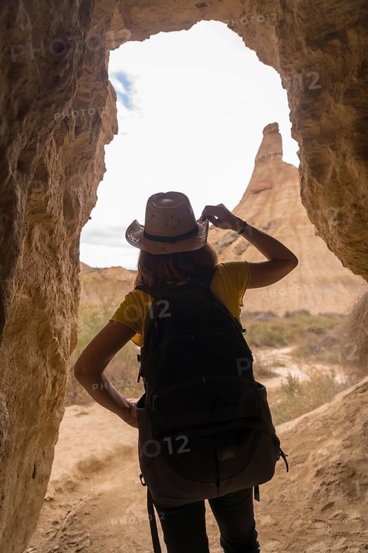 Vertical photo of the rear view of a woman into a cave in a desert