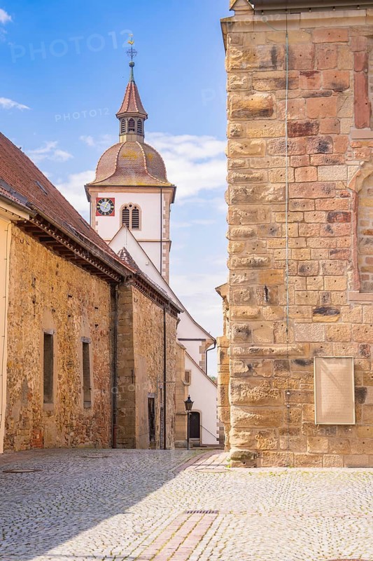 Combination of church and brick buildings with bell tower under a clear sky, Knittlingen, Germany