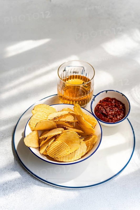 Crispy homemade chips served alongside a spicy dip and a refreshing drink, perfect for snacking. A delightful and appetizing treat for any occasion