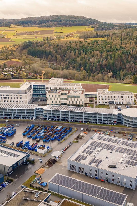Large modern building with solar systems in a rural area next to a forest, shortly in front of opening, Calw Health Campus, Calw District, Germany