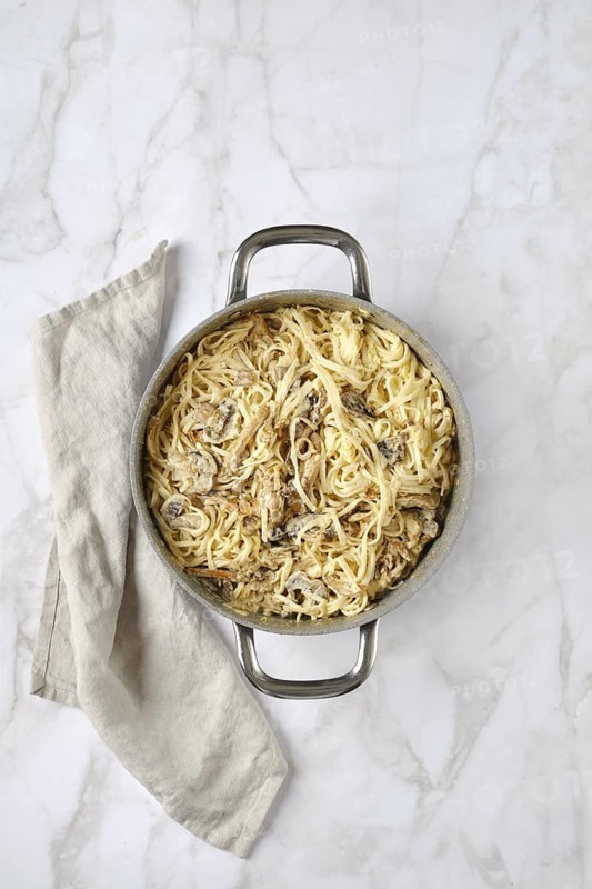 Overhead view of casserole with rice noodles and assortment of mushrooms and creamy sauce with cheese