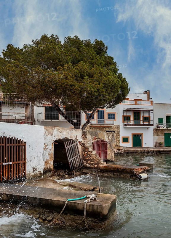 Old and dilapidated boat shelters that are not being used, old port area in Portocolom on the east coast of Majorca, Spain