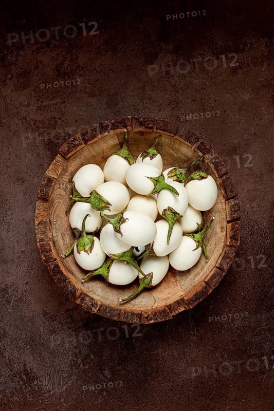 White mini eggplant, in a wooden bowl, on the table, close-up