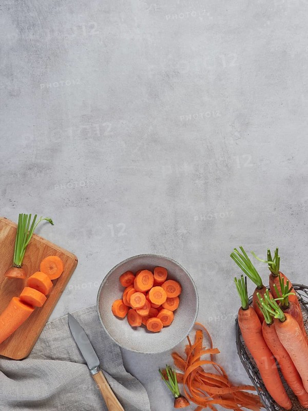 Top view of gray cement kitchen countertop with raw, whole and sliced carrots with copy space