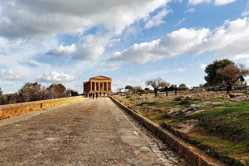 Walkers in front of Concordia Temple, Valley of the Temples, Agrigento, Sicily, Italy