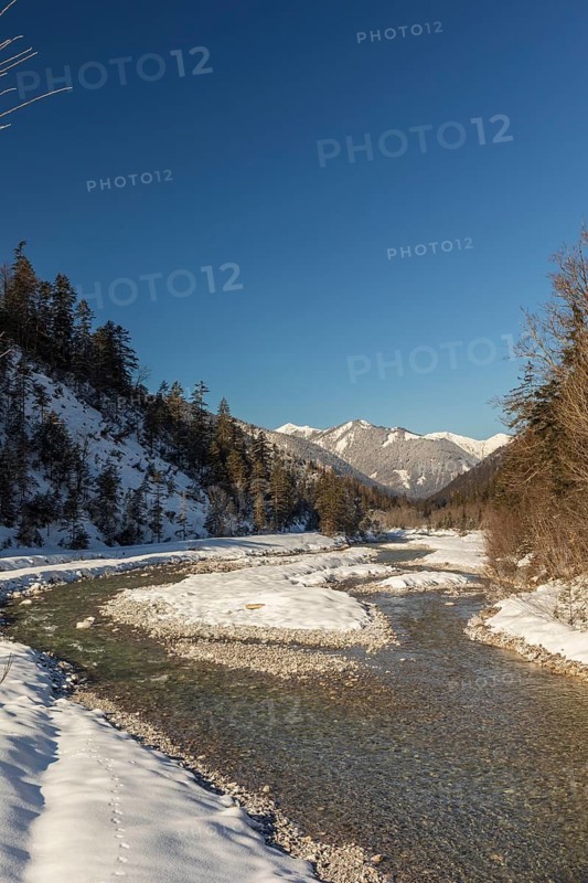 The Riss creek flowing through a snow covered landscape in the Eng valley. Sunny day with blue sky