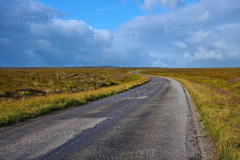A long, empty road runs through a vast grassland under a dramatic sky, Tongue, Lairg, Scotland, United Kingdom, Great Britain