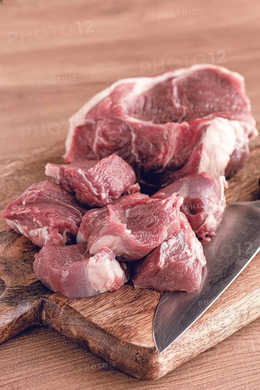 Raw beef meat, sliced on a cutting board, with a knife, no spices, no herbs, top view, wooden table, homemade, no people
