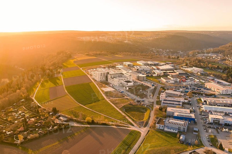 Comprehensive aerial view of a hilly landscape with buildings and fields in the evening light, new hospital at the Verbund Südwest Clinic, Calw, Germany