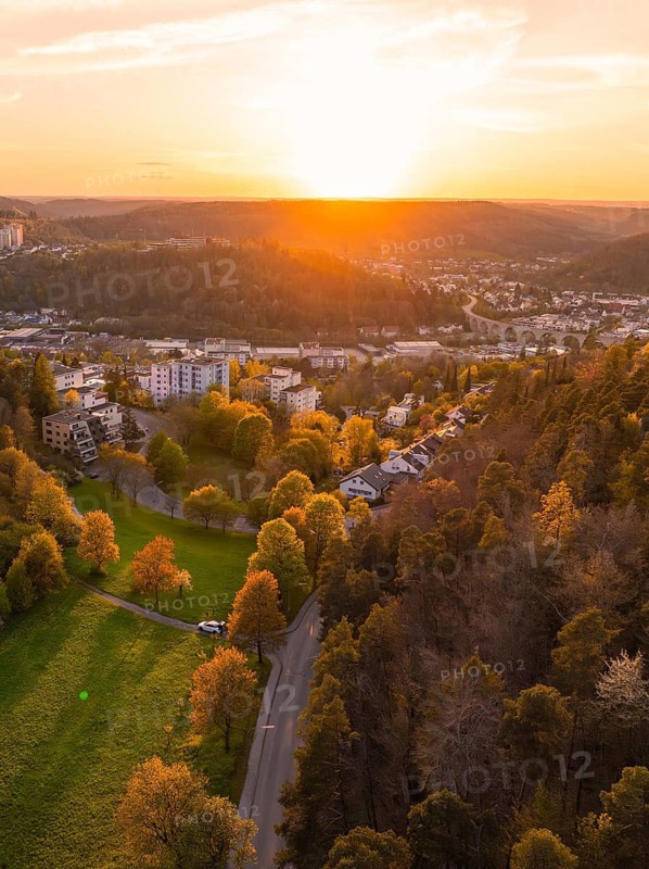 View of a hilly landscape with a town on the edge of a forest at sunset, Nagold, district of Calw, Germany