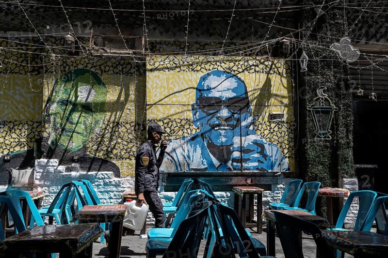 Cairo, Egypt. April 18th 2025. Empty cafe tables and a street art portrait of Naguib Mahfouz in Downtown Cairo, Egypt