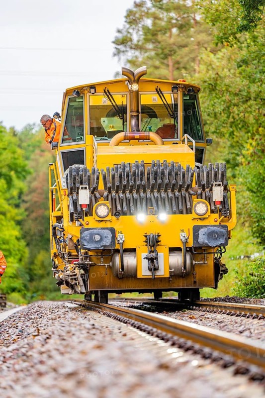 Railway working machine on tracks, surrounded by trees and workers, track construction Hermann Hesse Bahn, district of Calw, Black Forest, Germany
