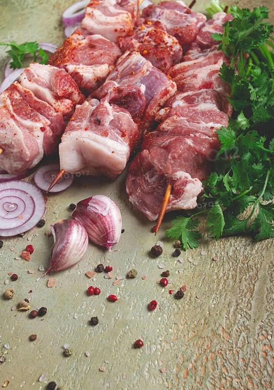 Raw pork meat, on wooden skewers, pickled kebab, with spices and herbs, on the table, top view, no people