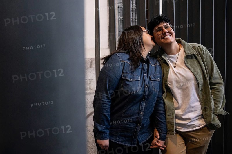 A joyful lesbian couple enjoys a tender moment outdoors. One woman conveys affection to her partner, showcasing love, diversity, and inclusion in a warm embrace