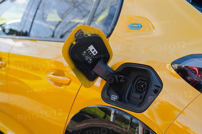 Close-up of an electric car in a vibrant yellow finish while charging. The plugged-in cable highlights eco-friendly and sustainable transportation technology