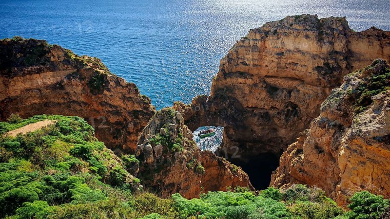 Cliffs and a cave with a boat in turquoise water against breathtaking scenery, Ponta da Piedade, Lagos, Algarve, Portugal