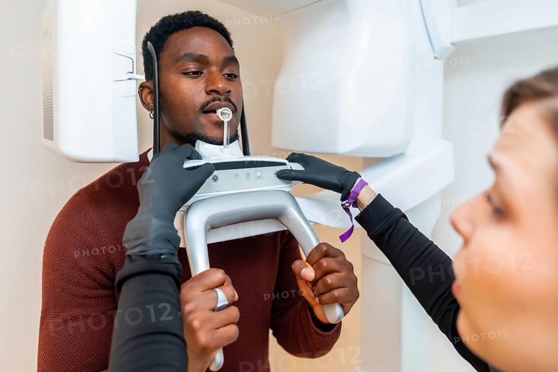 Dentist preparing a panoramic dental x ray scan for a male patient in a modern dental clinic