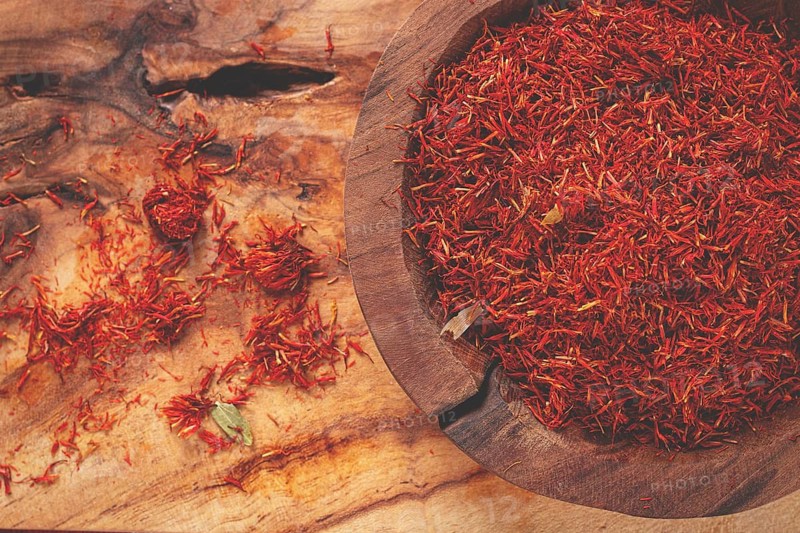 Spice saffron threads, in a wooden bowl, on a wooden table, top view, close-up