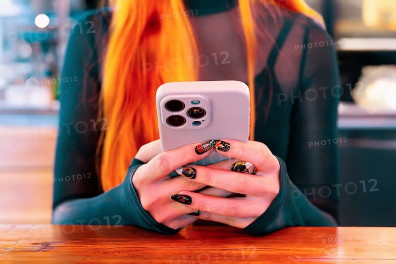 A woman with red hair and decorative nails holds a smartphone while exploring an Asian food market The scene captures the blend of tradition and modernity in a bustling environment