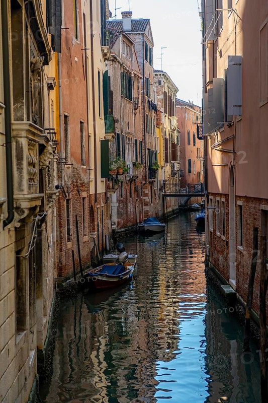Narrow canal with boats, houses reflected in the water, Venice, Veneto, Italy