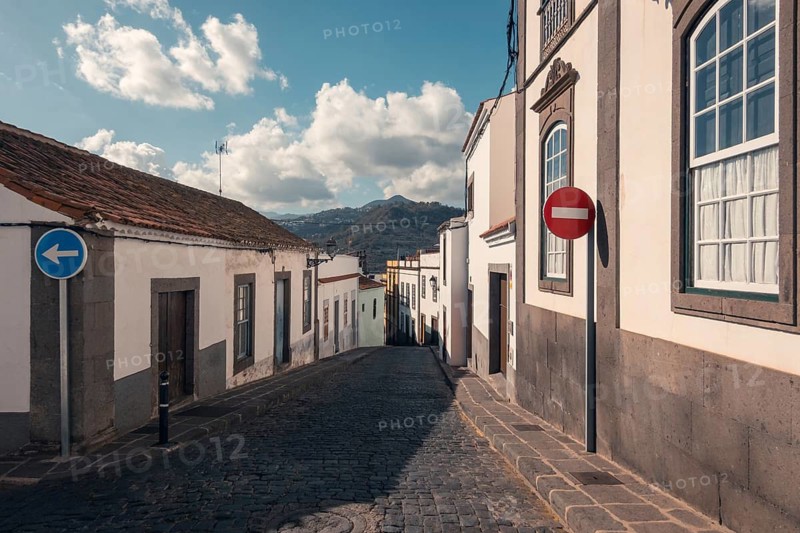A picturesque cobblestone street in Arucas, Gran Canaria showcases traditional architecture in the heart of the Canary Islands, with mountain views in the backdrop