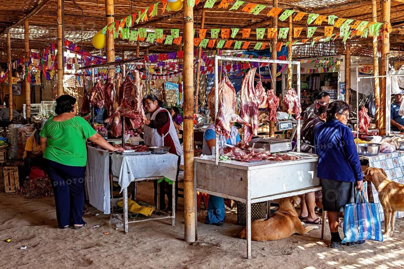 Market scene with meat stalls and visitors decorated with colorful flags and dogs, market and market stalls in the streets of Nasca in Peru