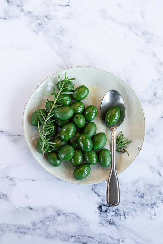Chalkidiki olives, classic Greek green olive, on a plate, with a spoon, top view, no people