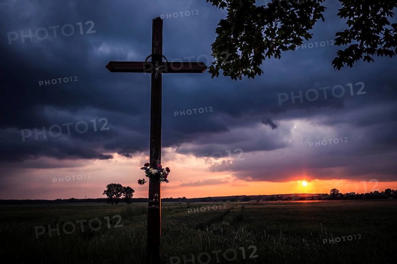 Wayside crucifix and sunset in the background in Tymowa, Poland