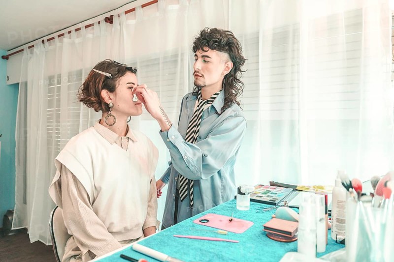 Professional makeup artist applying foundation on a model's face in a bright, modern beauty salon, highlighting diversity and inclusion in the beauty industry
