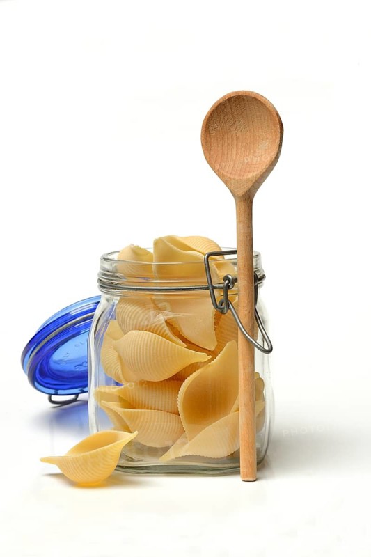 Conchiglione in glass jar with cooking spoon, Italian pasta variety