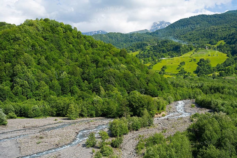 Picturesque landscape with a river running through forests and rolling mountains under cloudy sky, Racha-Lechkhumi region and Lower Svaneti, High Caucasus, Georgia