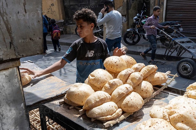 Cairo, Egypt. April 15th 2025. An Egyptian boy collects freshly baked traditional Baladi flat bread from a local bakery in Cairo, Egypt