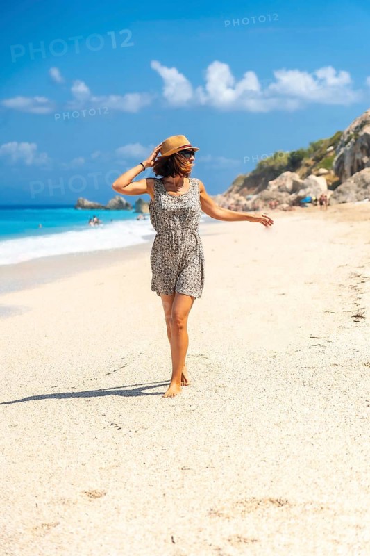 Portrait of woman with hat on Megali Petra beach with turquoise water of Lefkada island, Ionian Sea, Greece