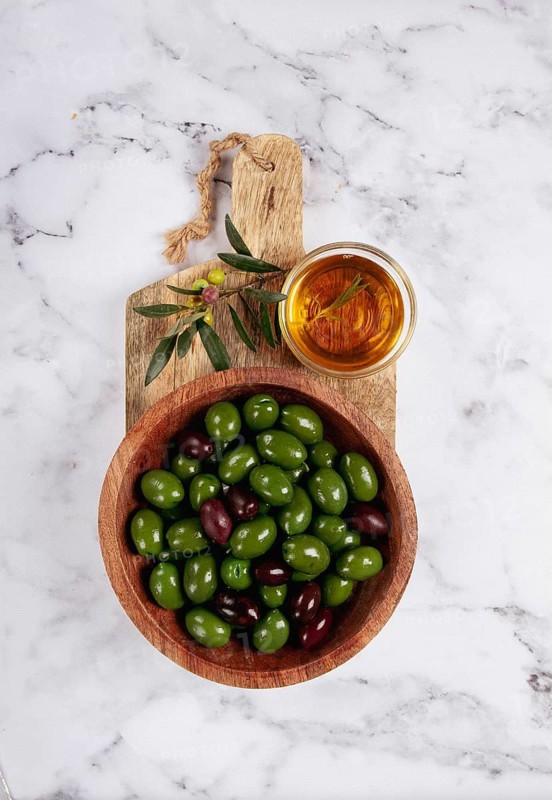 Chalkidiki olives, classic Greek green olives, in a bowl on a cutting board, top view, without people