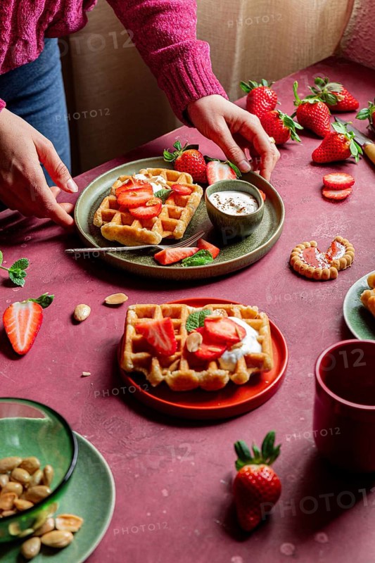 Delicious waffles topped with fresh strawberries and yoghurt on a rustic table. A romantic, homemade dessert that blends sweet flavors with an inviting aesthetic