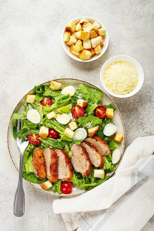 Caesar salad, with duck breast, on a light plate, on a light background, homemade, no people