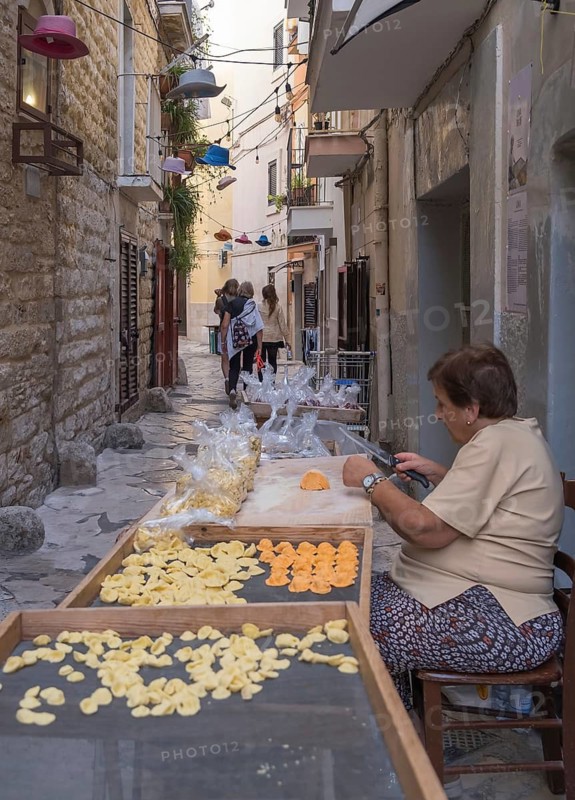A pasta maker at work in the famous Strada del Orecchiette, historic centre of Bari Vecchio, Apulia, Italy