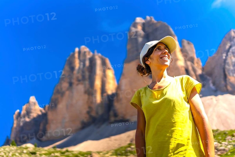 Female tourist enjoying the view of tre cime di lavaredo in the italian dolomites during a summer hike