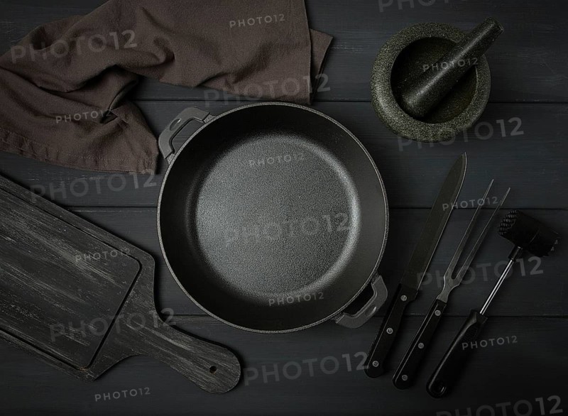 Cast iron brazier, with cooking utensils, for cooking, on a dark gray, wooden table, top view, horizontal, toned