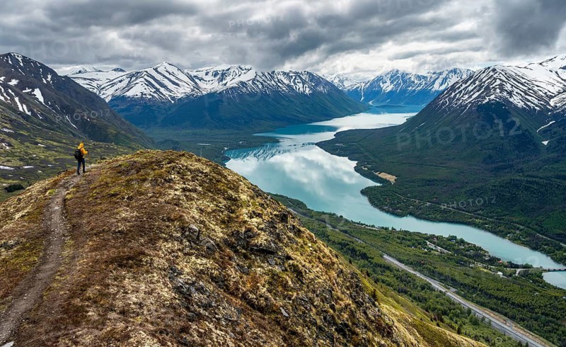 Climbers on a hiking trail on Slaughter Ridge, views of snowy mountains in spring and turquoise Lake Kenai Lake, Cooper Landing, Kenai Peninsula, Alaska, USA