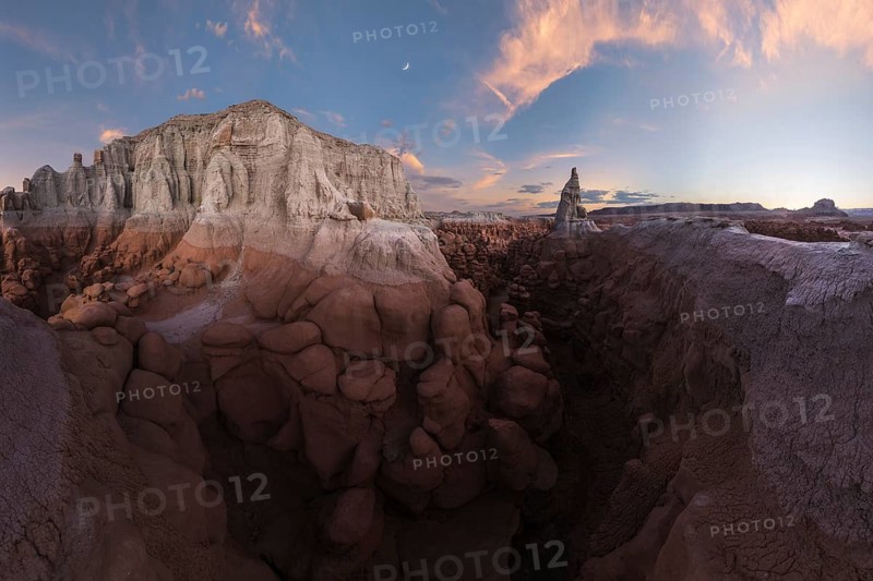 Scenic view of Goblin Valley State Park in Utah, showcasing unique sandstone formations under a dusky sky. The landscape is both dramatic and serene