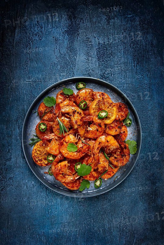 Grilled shrimp, unpeeled, headless, with spices, on a dark blue table, homemade, no people