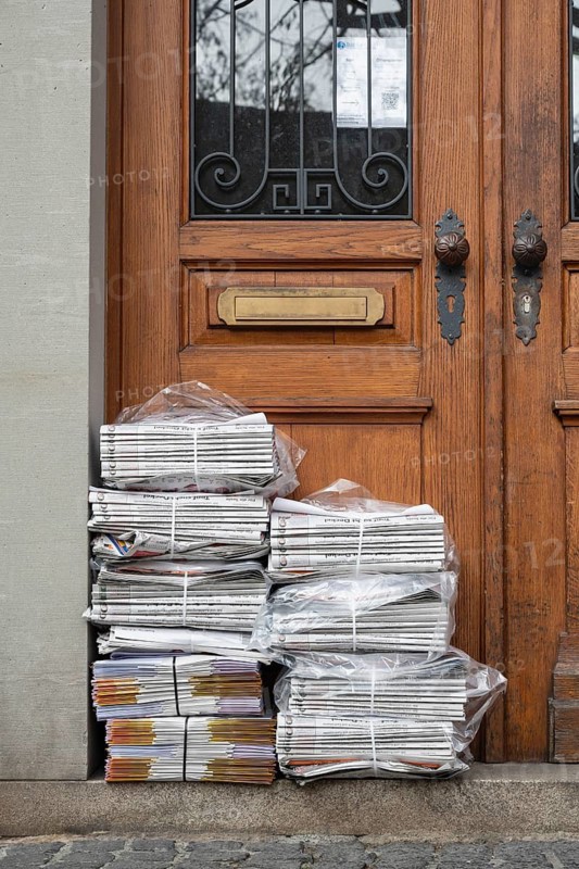 Stacks of newspapers bundled at an old front door in the historic old town of Constance, traditional craftsmanship, district of Constance, Baden-Württemberg, Germany