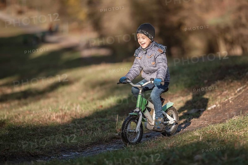 Six years old boy rides bicycle from the hill in the park